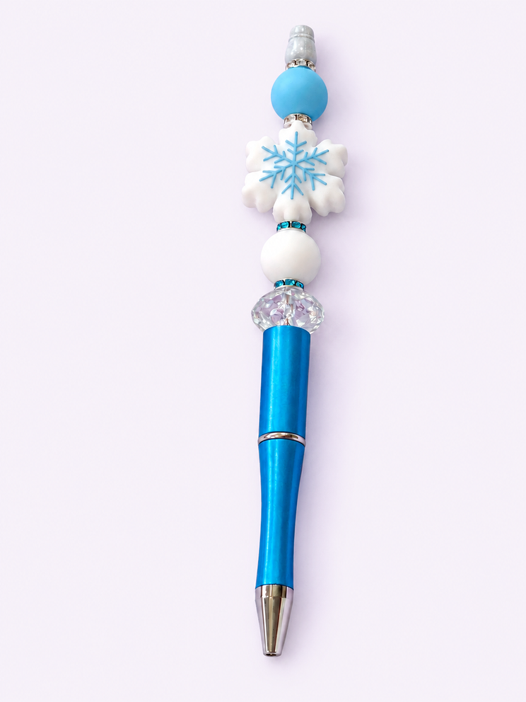 Upright blue pen with snowflake and blue beads on a pale lavender background